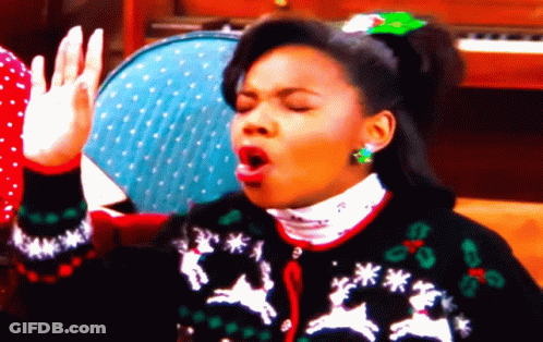 A Woman Wearing An Ugly Christmas Sweater With Reindeer And Snowflakes GIF