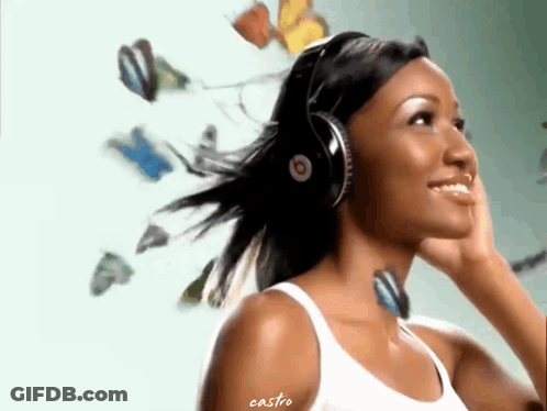A Woman Wearing Beats Headphones Is Smiling With Butterflies In The Background GIF