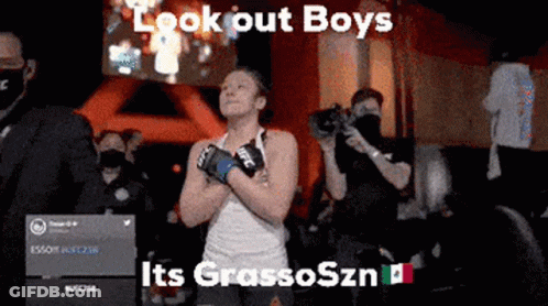 A Woman Wearing Boxing Gloves Is Standing In Front Of A Crowd And Says Look Out Boys GIF