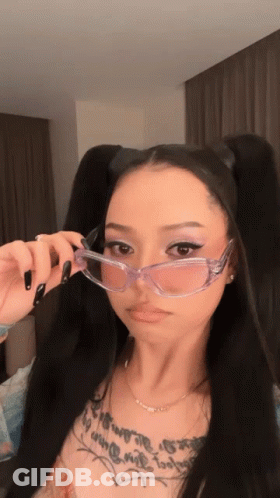 A Woman Wearing Clear Glasses Has A Tattoo On Her Chest GIF