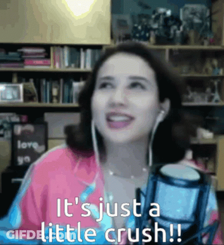 A Woman Wearing Ear Buds Is Smiling In Front Of A Microphone And The Words It 'S Just A Little Crush GIF