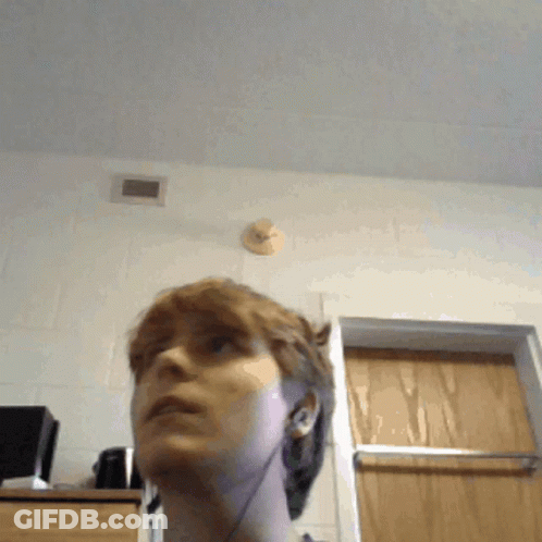 A Woman Wearing Ear Buds Looks Up At The Ceiling GIF