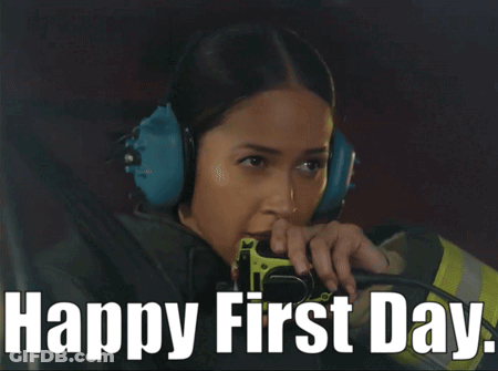 A Woman Wearing Ear Muffs Is Holding A Fire Extinguisher With The Words Happy First Day Below Her GIF