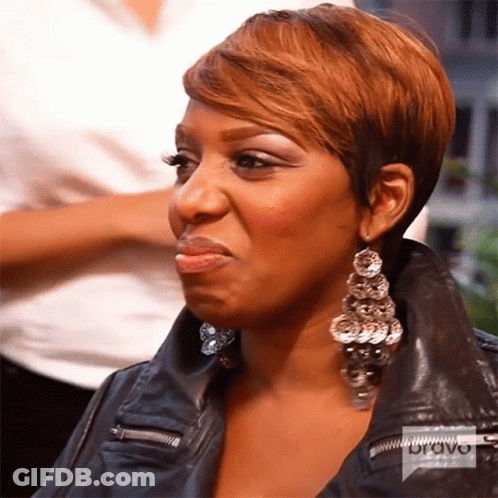 A Woman Wearing Earrings And A Leather Jacket Has A Bravo Logo On Her Jacket GIF