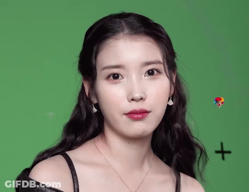 A Woman Wearing Earrings And A Necklace Looks At The Camera GIF