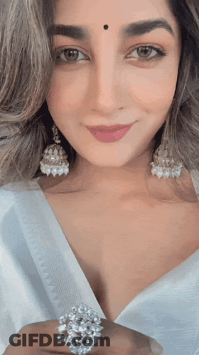A Woman Wearing Earrings And A Ring Is Smiling GIF