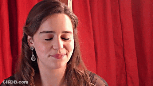 A Woman Wearing Earrings Is Smiling With Her Eyes Closed GIF