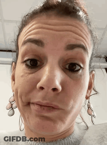 A Woman Wearing Earrings Makes A Funny Face With Her Eyes Closed GIF