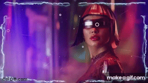 A Woman Wearing Futuristic Glasses And A Helmet Is Standing In A Dark Room . GIF