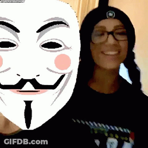 A Woman Wearing Glasses And A Beanie Stands Next To A Mask With A Mustache And Eyebrows GIF