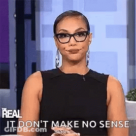 A Woman Wearing Glasses And A Black Dress Is Making A Funny Face While Sitting On A Stage . GIF