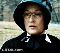 A Woman Wearing Glasses And A Black Hat With A Bow Tie GIF