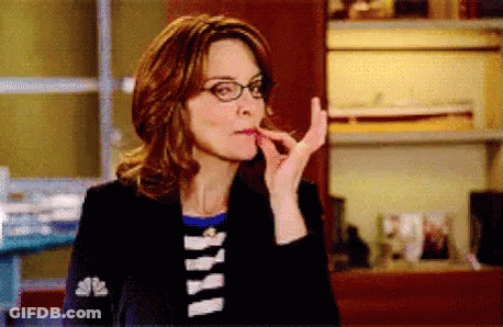 A Woman Wearing Glasses And A Black Jacket Is Eating Something . GIF