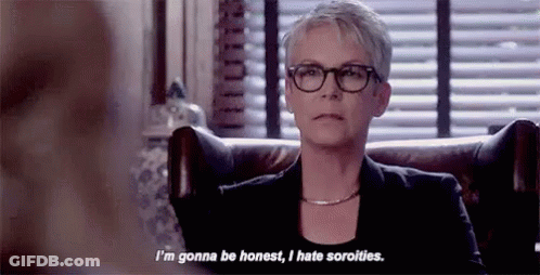 A Woman Wearing Glasses And A Black Jacket Is Sitting In A Chair And Talking To Someone . GIF