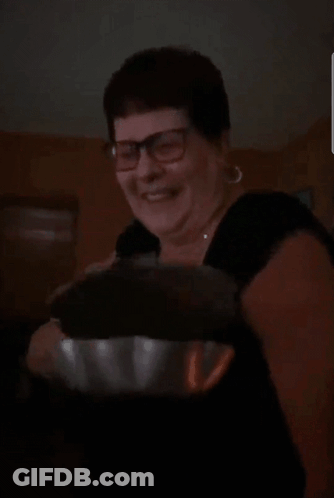 A Woman Wearing Glasses And A Black Shirt Is Smiling And Holding A Bowl GIF