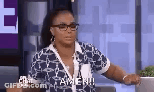 A Woman Wearing Glasses And A Blue Shirt Is Sitting On A Couch . GIF