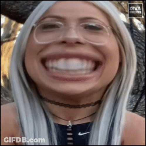 A Woman Wearing Glasses And A Choker Makes A Funny Face In Front Of Diva Digital GIF