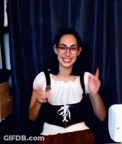 A Woman Wearing Glasses And A Corset Is Smiling And Giving A Thumbs Up Sign . GIF