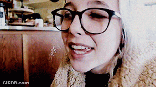 A Woman Wearing Glasses And A Fur Coat Smiles At The Camera GIF