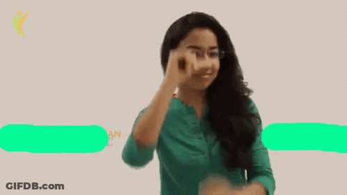 A Woman Wearing Glasses And A Green Shirt Points Her Finger Up GIF