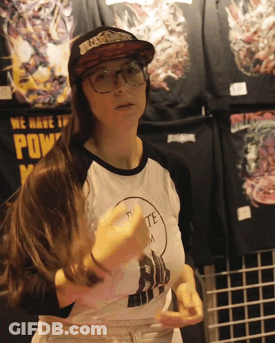 A Woman Wearing Glasses And A Hat Stands In Front Of A Sign That Says ' We Have The Power ' GIF