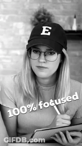 A Woman Wearing Glasses And A Hat With The Letter E On It Is 100 % Focused GIF