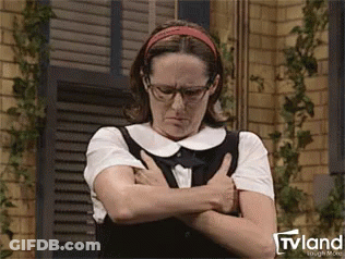 A Woman Wearing Glasses And A Headband Is Standing With Her Arms Crossed And Looking Down . GIF