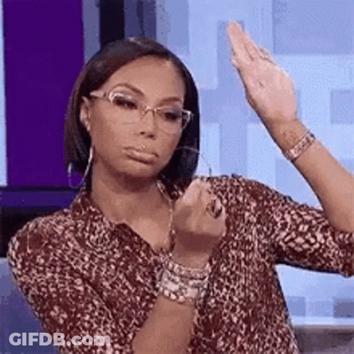 A Woman Wearing Glasses And A Leopard Print Shirt Is Holding Her Hand Up In The Air . GIF