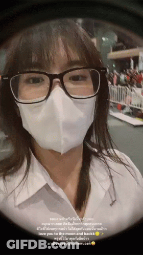 A Woman Wearing Glasses And A Mask Has A Message In Another Language GIF