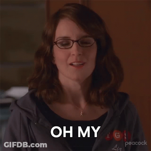 A Woman Wearing Glasses And A Peacock Sweatshirt Says " Oh My " GIF
