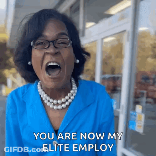 A Woman Wearing Glasses And A Pearl Necklace Is Screaming With Her Mouth Wide Open . GIF