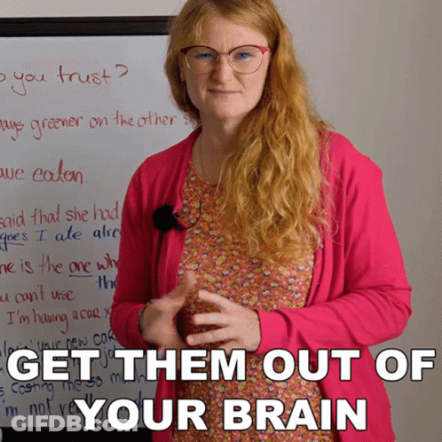 A Woman Wearing Glasses And A Pink Cardigan Stands In Front Of A White Board That Says Get Them Out Of Your Brain GIF
