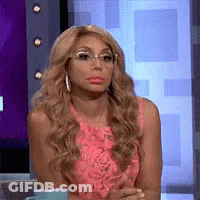 A Woman Wearing Glasses And A Pink Dress Is Sitting In Front Of A Television Screen . GIF