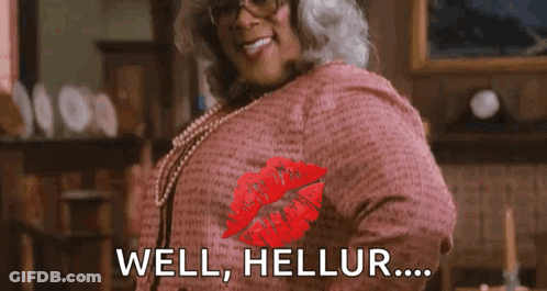 A Woman Wearing Glasses And A Pink Shirt Is Giving A Kiss With The Words `` Well , Hellur ... '' . GIF