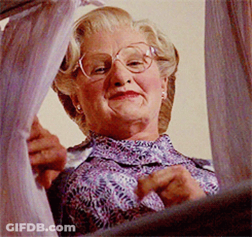 A Woman Wearing Glasses And A Purple Shirt Is Looking Out A Window GIF