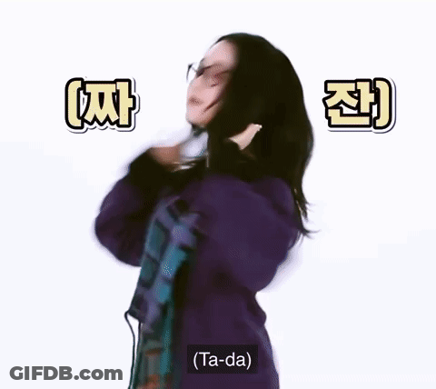 A Woman Wearing Glasses And A Purple Sweater Is Dancing And Says Ta-Da . GIF