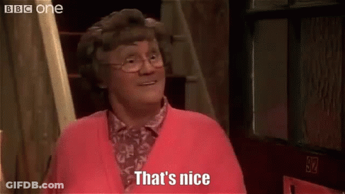 A Woman Wearing Glasses And A Red Sweater Is Standing In Front Of A Door And Says `` That 'S Nice '' . GIF