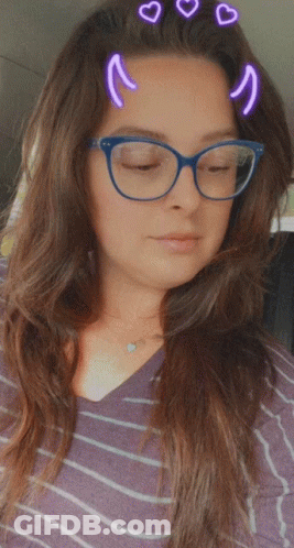 A Woman Wearing Glasses And A Striped Shirt Has Hearts On Her Hair GIF