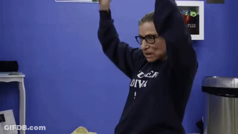 A Woman Wearing Glasses And A Sweatshirt That Says " Car Diva " Is Dancing In A Room . GIF