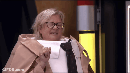 A Woman Wearing Glasses And A Trench Coat Holds Up A Piece Of Paper GIF