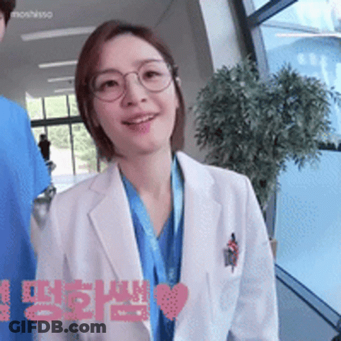 A Woman Wearing Glasses And A White Coat Has A Heart In The Corner GIF