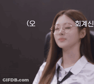A Woman Wearing Glasses And A White Shirt Is Sitting In A Chair GIF