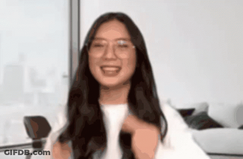 A Woman Wearing Glasses And A White Shirt Smiles For The Camera GIF