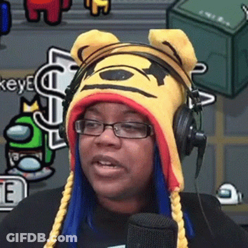 A Woman Wearing Glasses And A Winnie The Pooh Hat Is Talking Into A Microphone . GIF