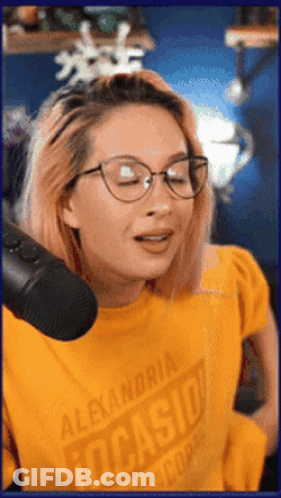 A Woman Wearing Glasses And A Yellow Shirt That Says Alexandria Tucasio GIF