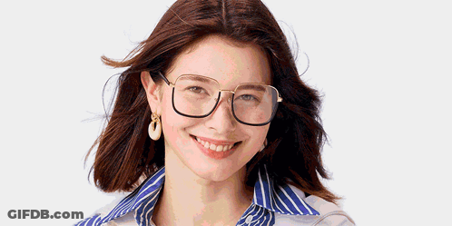 A Woman Wearing Glasses And Earrings Is Smiling GIF