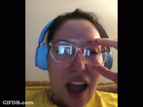 A Woman Wearing Glasses And Headphones Holds Her Hand To Her Face GIF