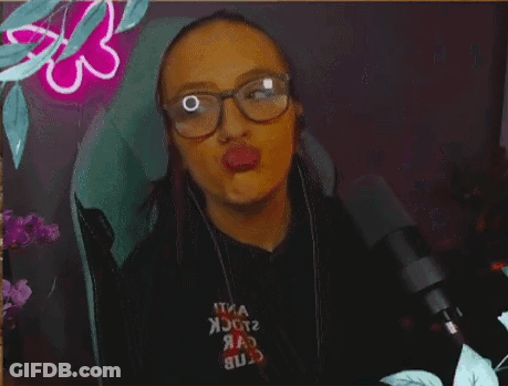 A Woman Wearing Glasses And Headphones Is Blowing A Kiss GIF