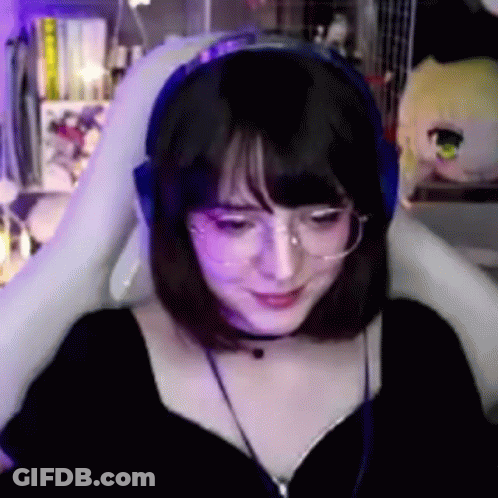 A Woman Wearing Glasses And Headphones Is Sitting In A Chair . GIF