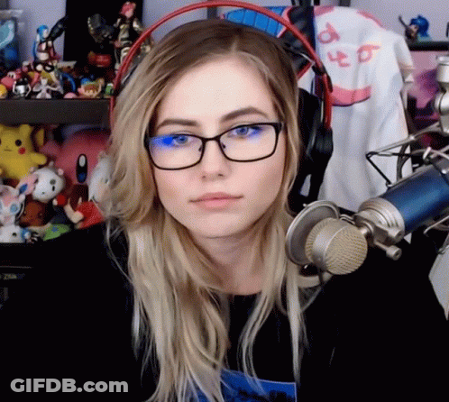 A Woman Wearing Glasses And Headphones Is Sitting In Front Of A Microphone GIF